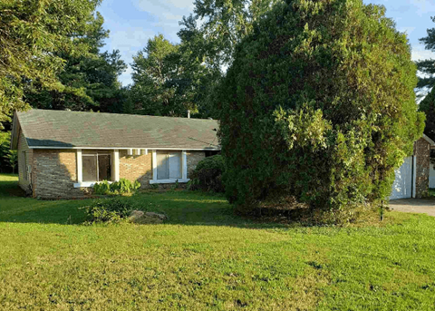 a small brick house with a lawn and a tree